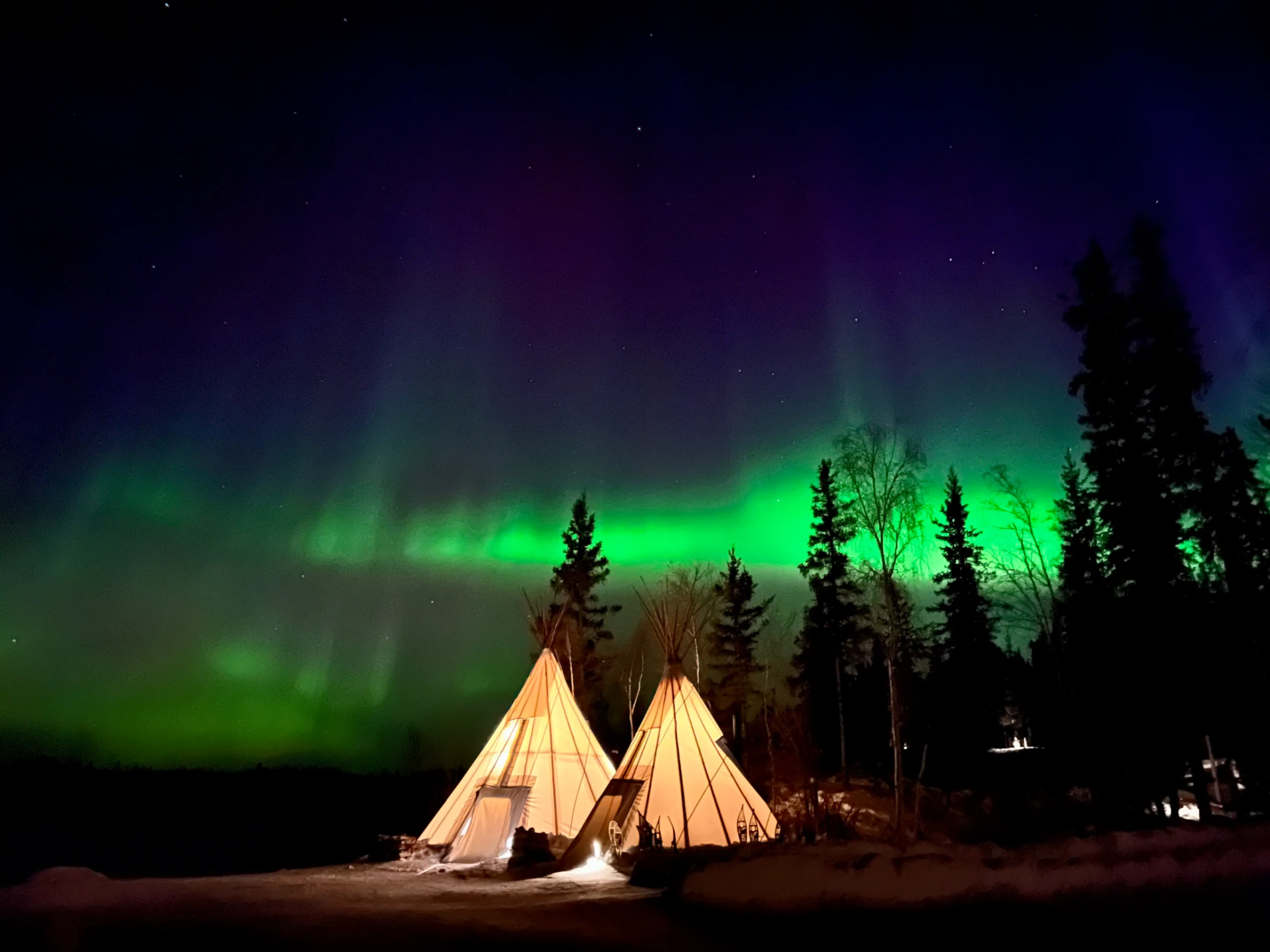 Cực quang chiếu sáng những chiếc lều và khu rừng trong đêm ở Yellowknife, Canada