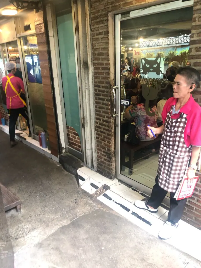 巷口熱炒店門口，玻璃上有貓的歡迎標誌