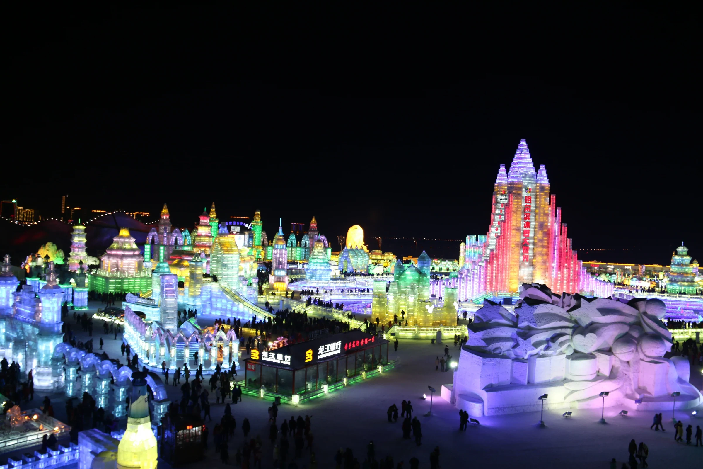 哈爾濱冰雪大世界歷年冰雕建築於夜晚亮起彩色燈光的廣角景象