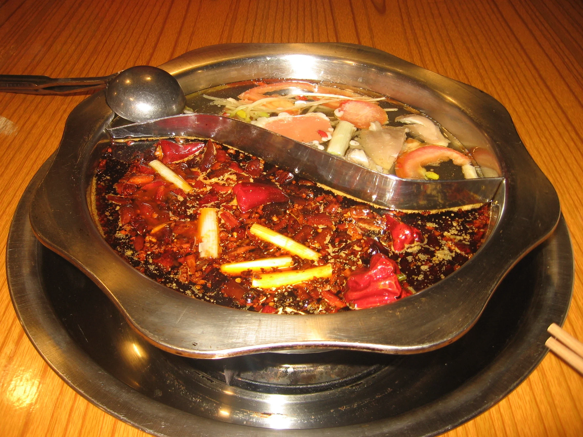 Chongqing divided hotpot with a red chili-oil broth on one side and clear broth on the other