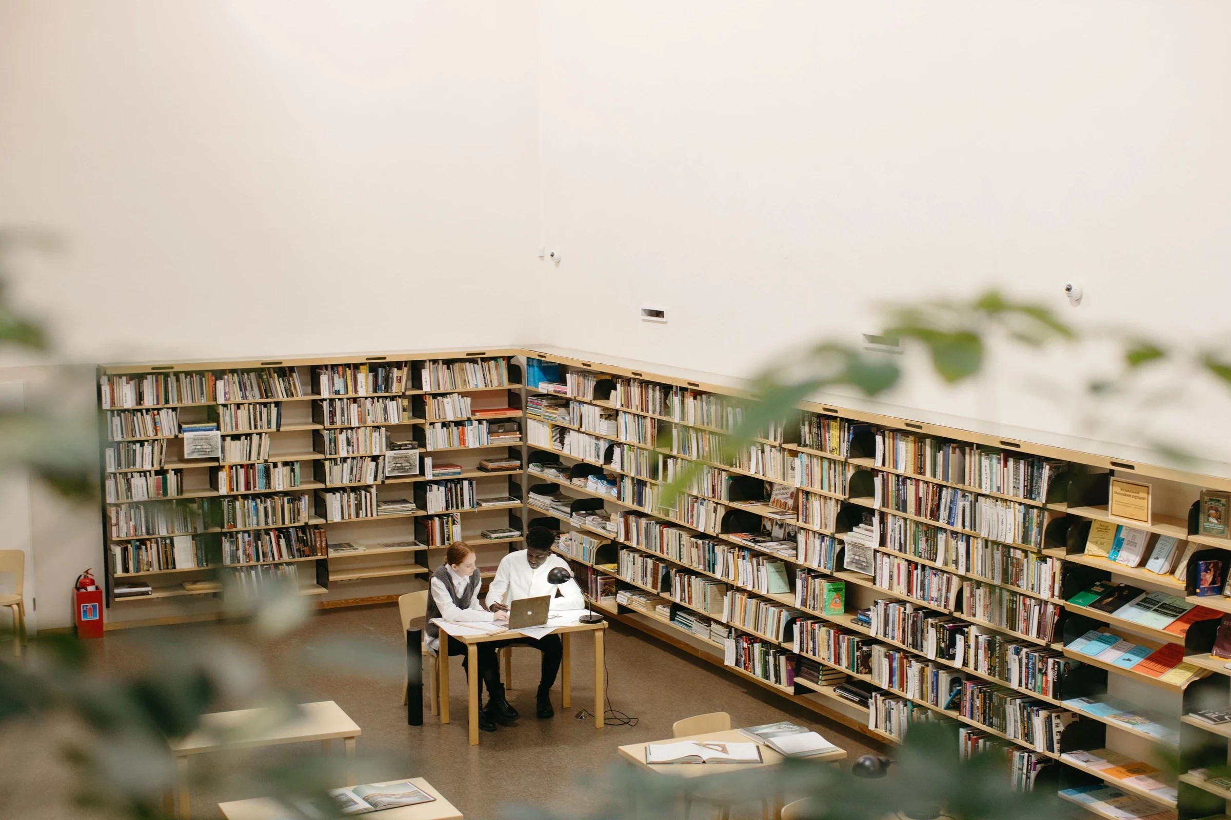 學生在圖書館桌邊一起使用筆電讀書