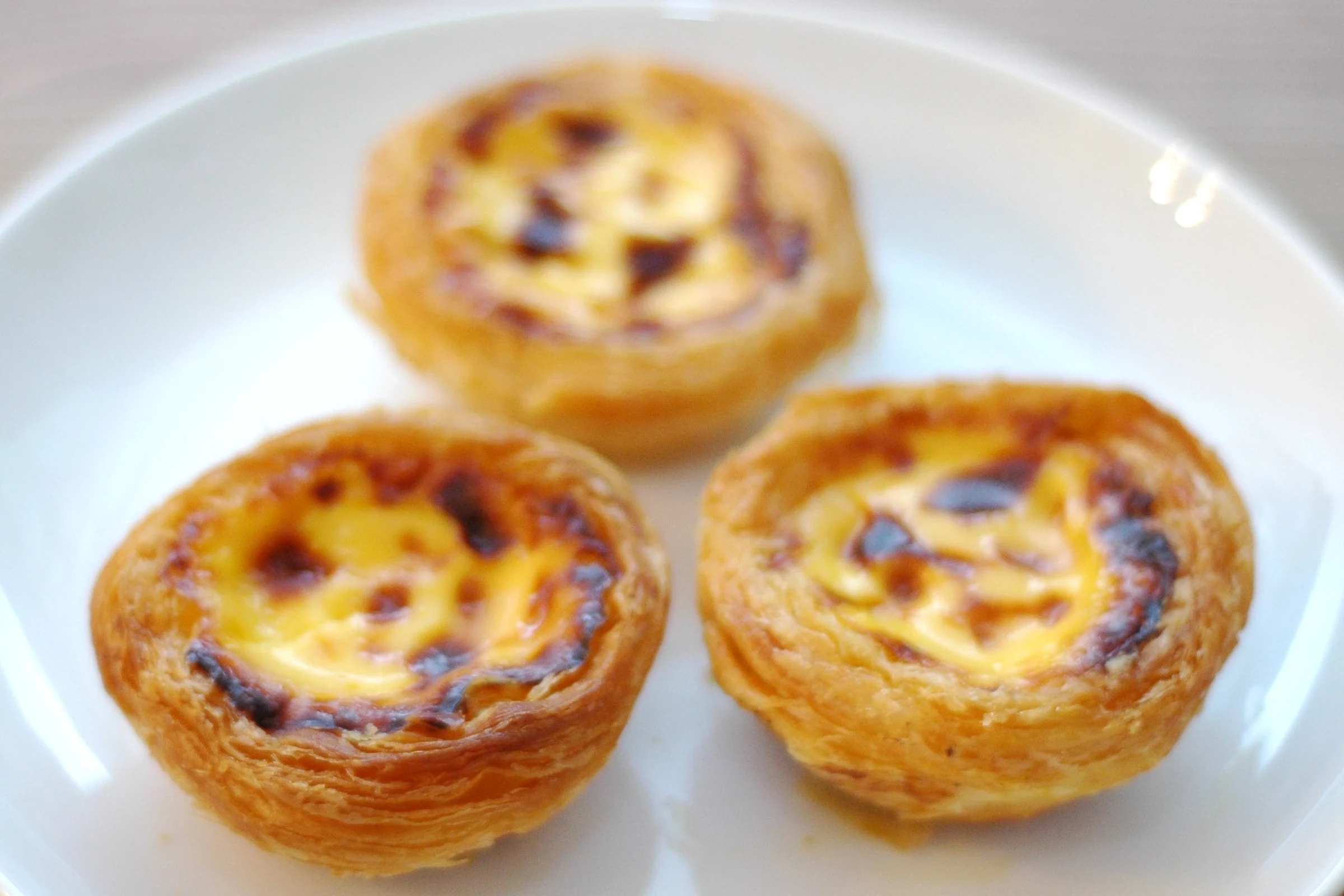 Three egg tarts from Margaret's Cafe e Nata on a white plate in 2009