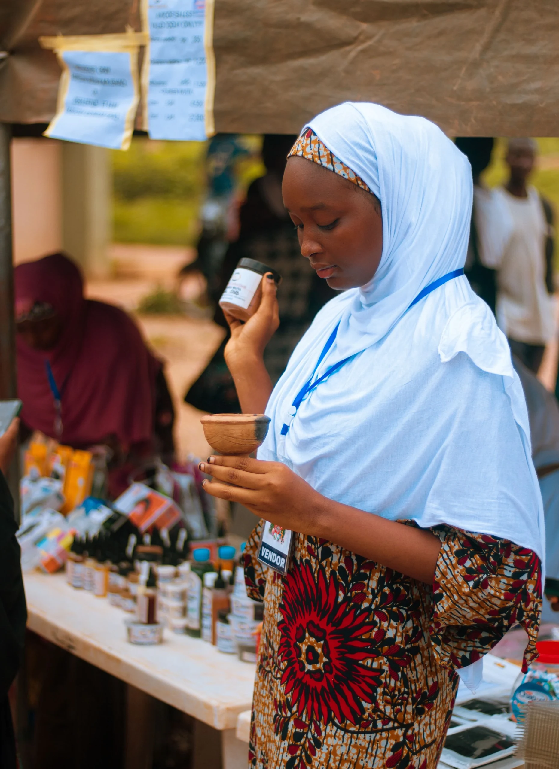 A stallholder checking products in hand in front of an outdoor market stall