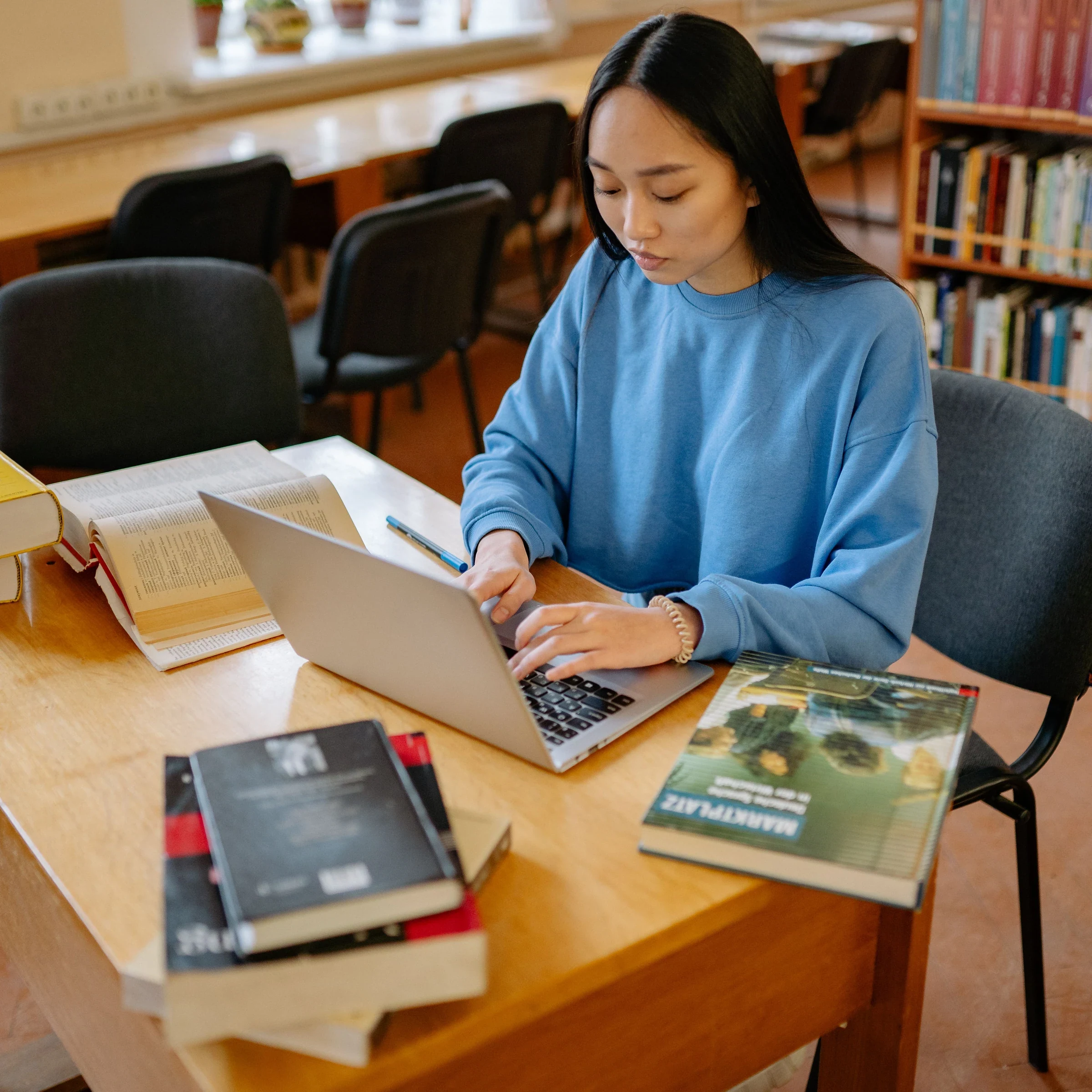 學生在圖書館用筆電，桌上有書本