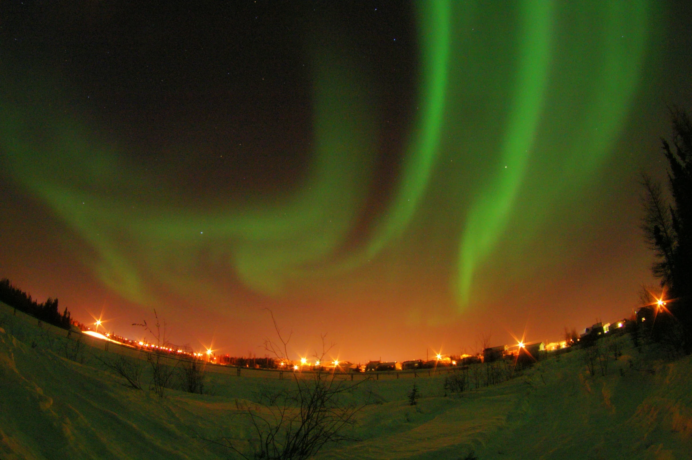 Cực quang màu xanh lá trên bầu trời đêm Yellowknife cùng ánh đèn thị trấn